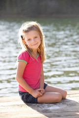 Young girl sitting by lake