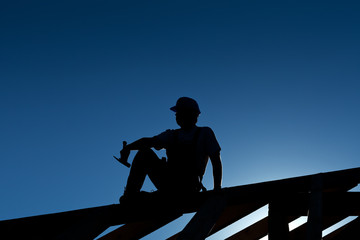 Builder or carpenter resting on top of roof structure
