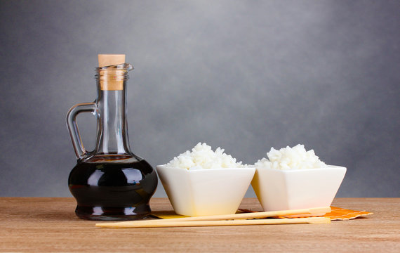 Bowls Of Cooked Rice And Soy Sauce In Jar On Wooden Table