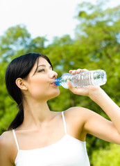 Young woman drinking water at workout, outdoors