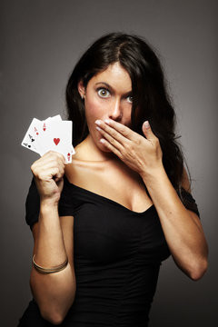 mujer jugando al poker con poker de ases en la mano sorprendida