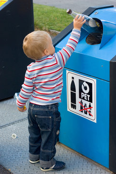 child putting waste in bin
