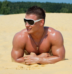 Muscle sexy wet naked young man lying on the sands