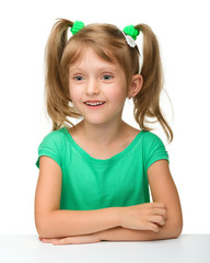 Little girl is sitting at table in astonishment