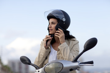 Attraktive Frau auf Roller zieht ihren Helm aus