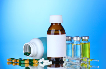 Medical bottles, ampoules and pills on blue background
