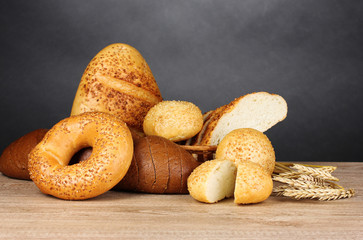rye and white bread and buns on wooden table on gray background