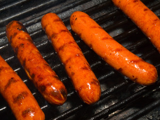 A row of five hotdogs on a bbq grill - obrazy, fototapety, plakaty