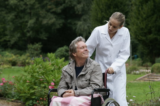 Älterer Herr im Rollstuhl mit Pflegekraft