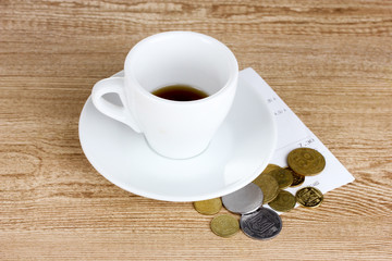 Empty cup of coffee with coins tip on wooden background. Ukraini