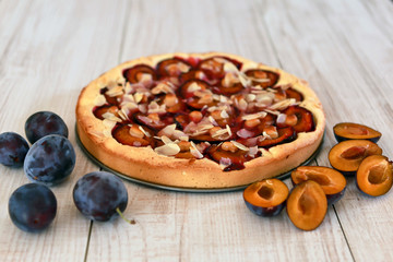Plum pie and plums on a wooden white background