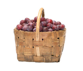 Wattled basket with ripe plums on white background