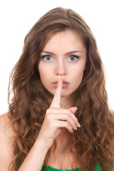 Naklejka premium portrait of attractive teenage girl with finger on lips,