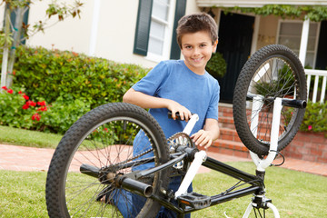 Fototapeta na wymiar boy fixing bike in garden