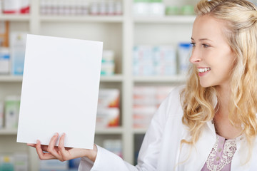 lächelnde apothekerin zeigt weißes schild