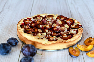 Plum pie and plums on a wooden background