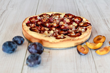 Plum pie and plums on a wooden background