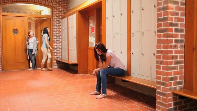 Lonely young student watching her classmates passing