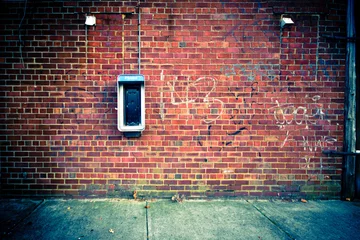Deurstickers Graffiti Verouderde telefooncel op een grungy stedelijke bakstenen muur