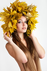 A girl with a wreath of autumn leaves on the head.