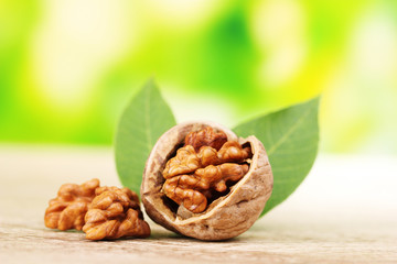 walnuts and leaves on wooden table on green background