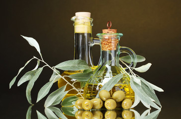 olive oil in jars and olives on yellow background