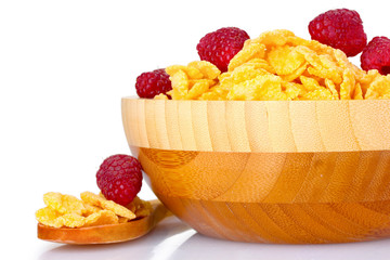 tasty cornflakes and raspberries in wooden bowl