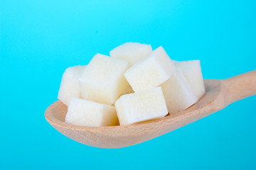 refined sugar in wooden spoon on blue background