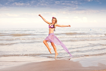 Fototapeta na wymiar Beautiful young jumping woman near the sea
