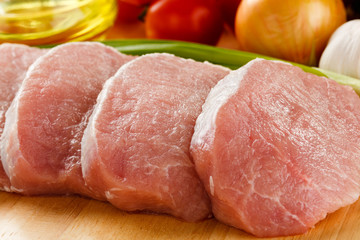 Raw pork on cutting board and vegetables