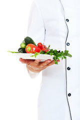 chef holding plate with vegetables