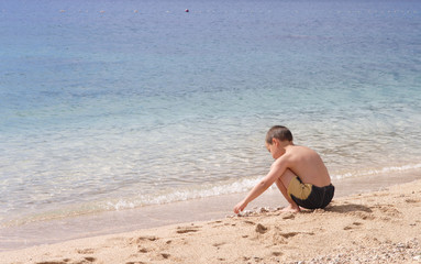 little boy playing with pebbles on a clean empty beach