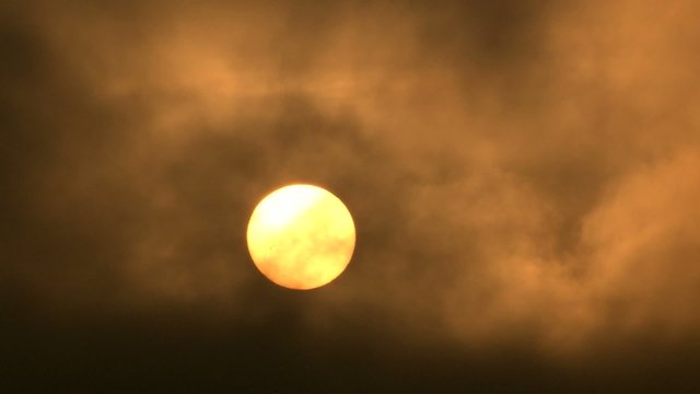 Sun rising, dark clouds flying through.