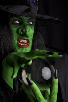 Evil witch and her crystal ball, black background.