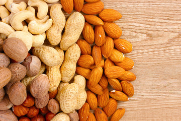 nutmeg, peanuts, hazelnuts and almonds on wooden background