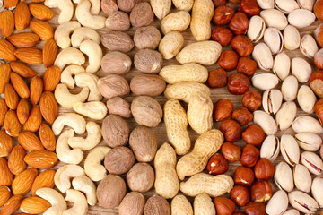 nutmeg, peanuts, hazelnuts and almonds on wooden background