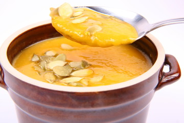 Bowl of pumpkin soup being eaten with a spoon