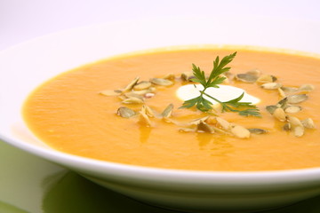 Pumpkin soup decorated with cream, pumpkin seeds and parsley
