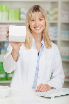 lächelnde apothekerin zeigt weiße packung