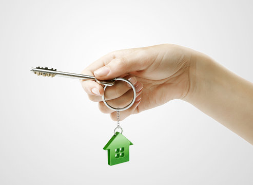Hand holding key with a keychain in the shape of the house