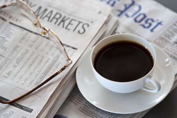 Hot coffee and newspaper. reading glasses