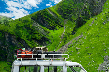 Tourists backpacks and equipment on car trunk in mountains