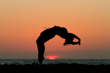 silhouette of gymnast in sunset at beach