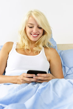 Woman sitting in bed texting