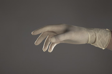 mano con guante de latex en fondo gris aislado