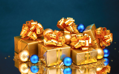 Beautiful gifts in gold packaging and Christmas balls on blue ba