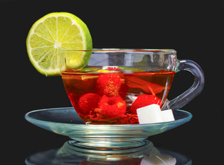 black tea, lime and raspberry in cup on black background