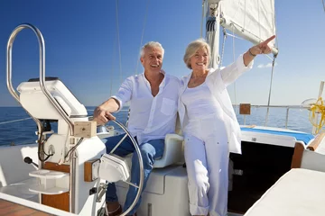 Fototapeten Happy Senior Couple At The Wheel of a Sail Boat © spotmatikphoto