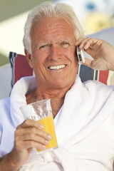 Handsome Senior Man Talking on Cell Phone Drinking Orange Juice