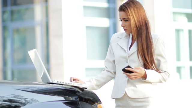 Attractive business woman using mobile phone and laptop